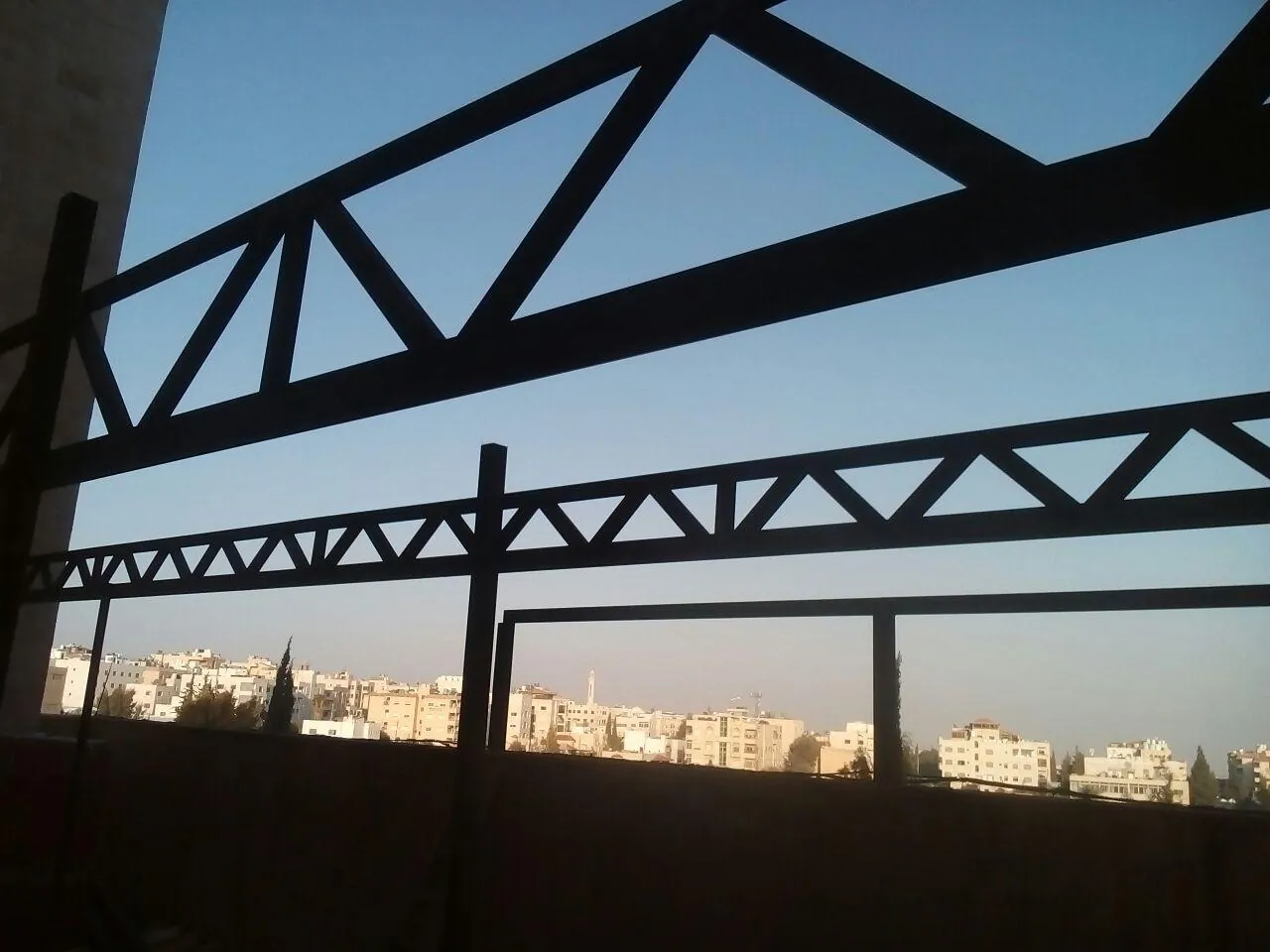 Steel roof trusses being installed over Amman at sunset